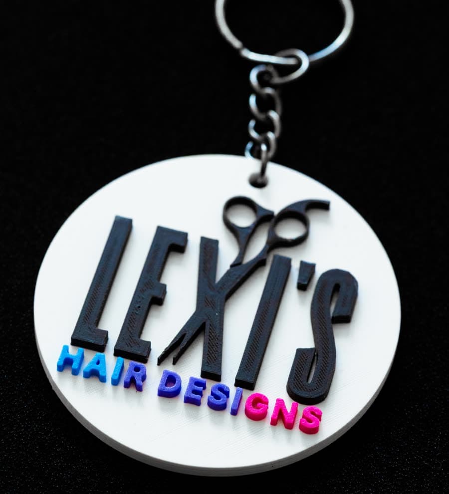 Un llavero redondo con el logotipo en relieve de una peluquería